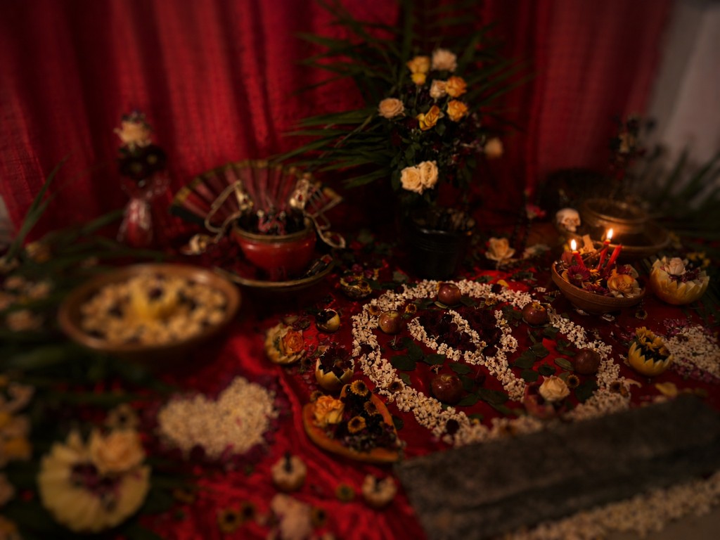 Mesa ritual com tecido vermelho, oferendas de pipoca em espiral, velas, rosas e frutas — ambiente de trabalho espiritual amoroso